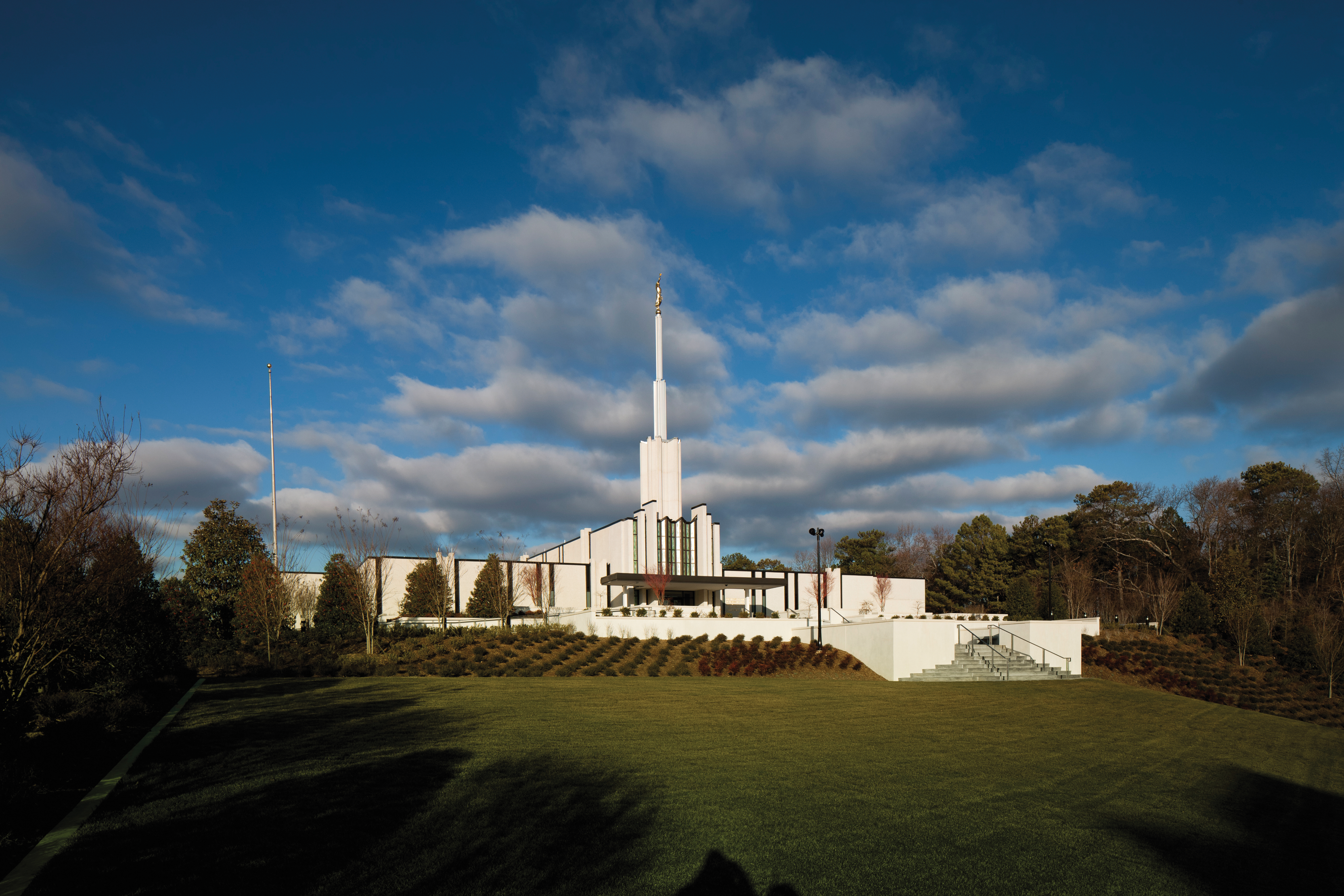 The Atlanta Georgia Temple in the daytime, with a green lawn in the foreground and small gray clouds overhead.