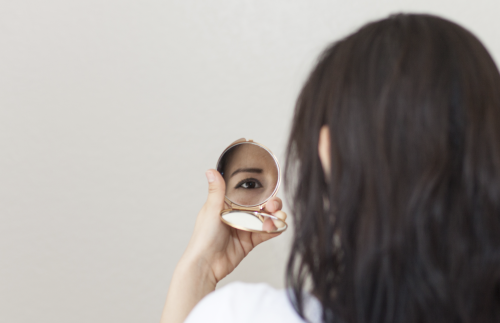 Woman Looking at Herself in Small Hand Mirror