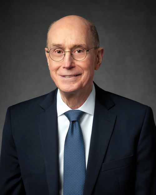 A portrait of President Henry B. Eyring wearing a black suit and a blue tie.
