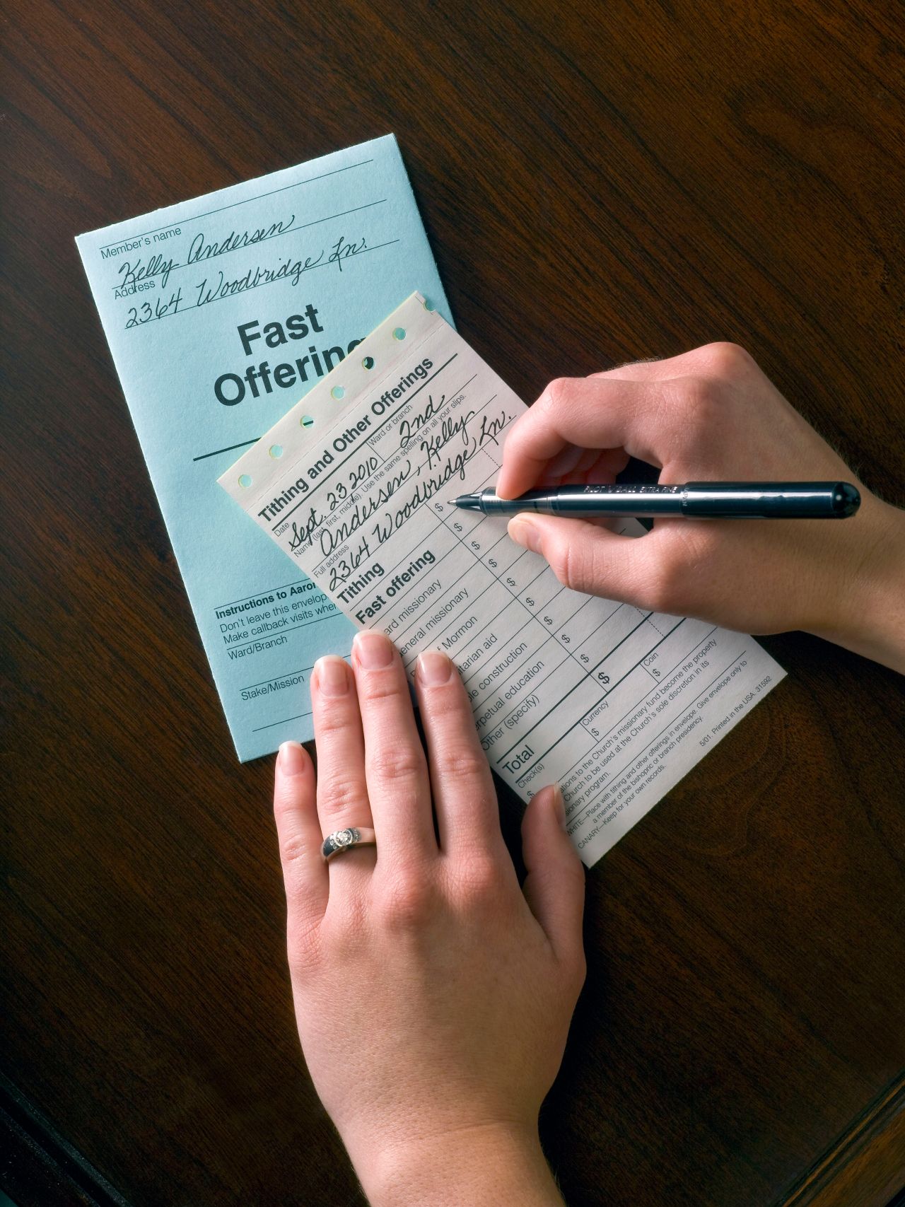 A woman fills out her tithing slip at her kitchen table