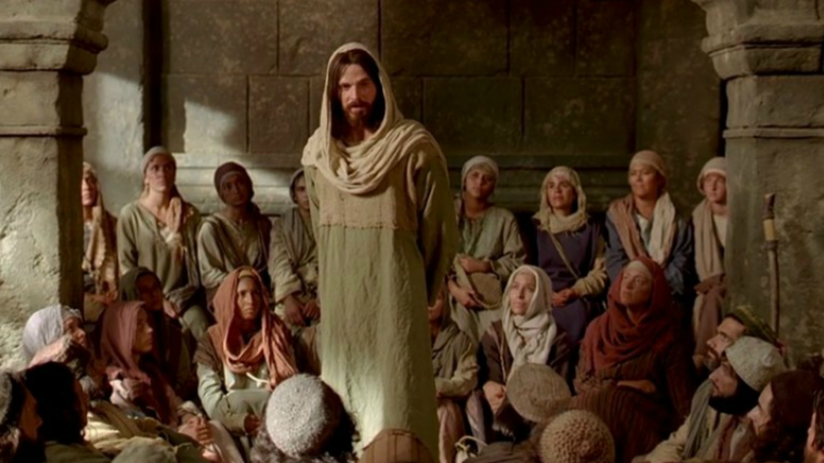 Jesus Christ teaching a group of people seated around Him.