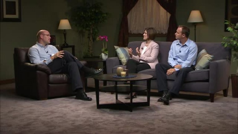 A mother and father talk to an interview on a living room set