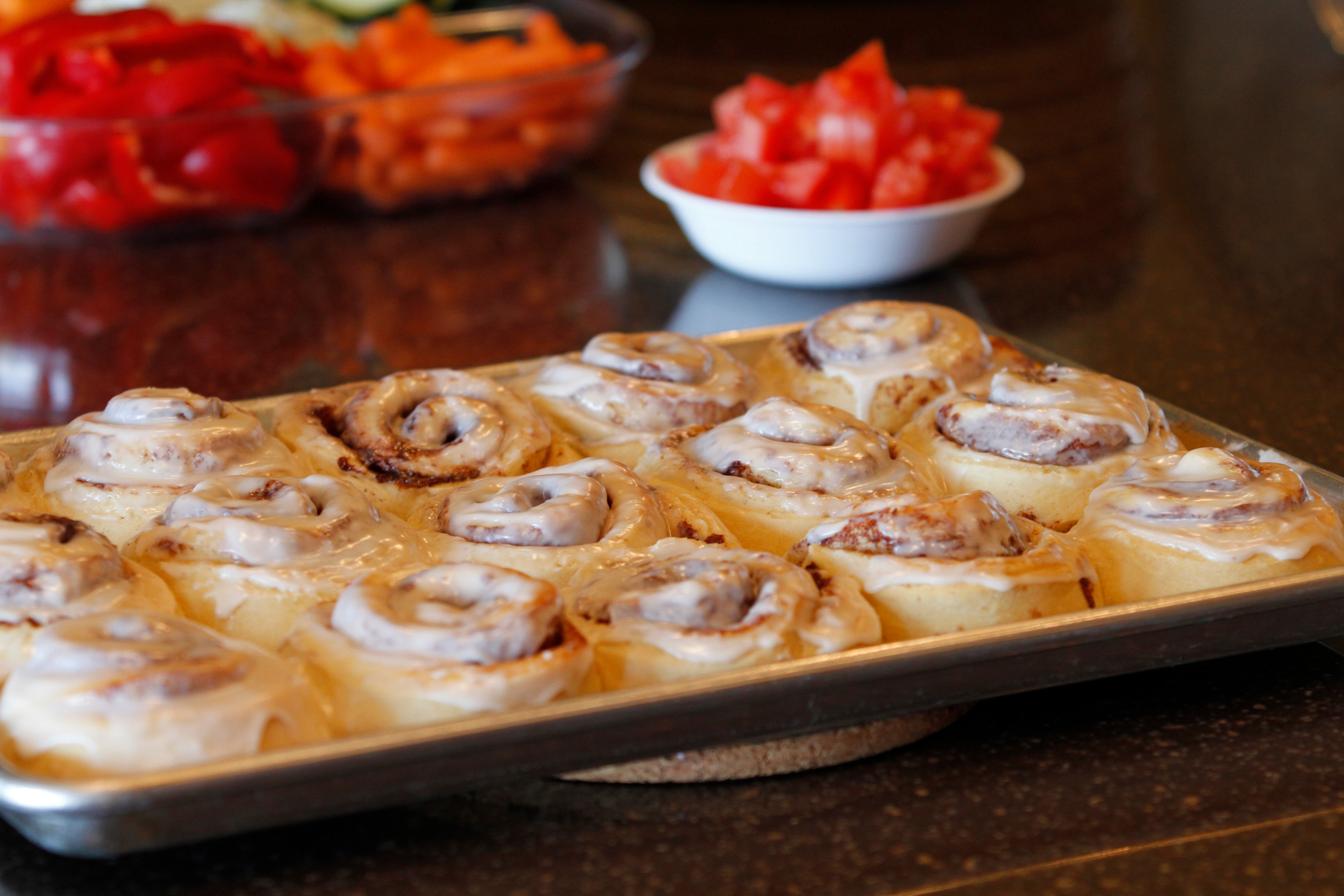 A pan of hot cinnamon rolls with icing on top, melting.