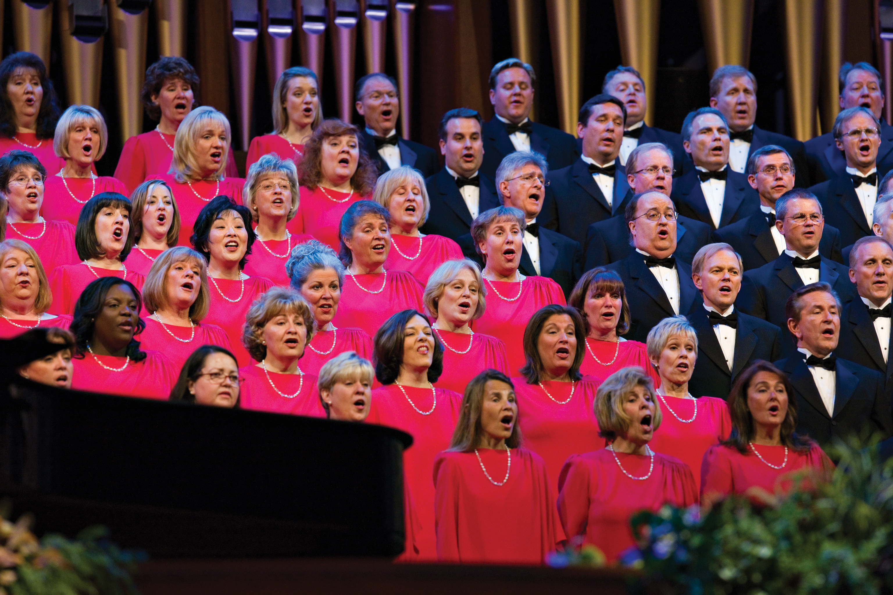 The Mormon Tabernacle Choir, with the women in red dresses and the men in black suits, singing in the Pioneer Day Commemoration Concert in July 2008.