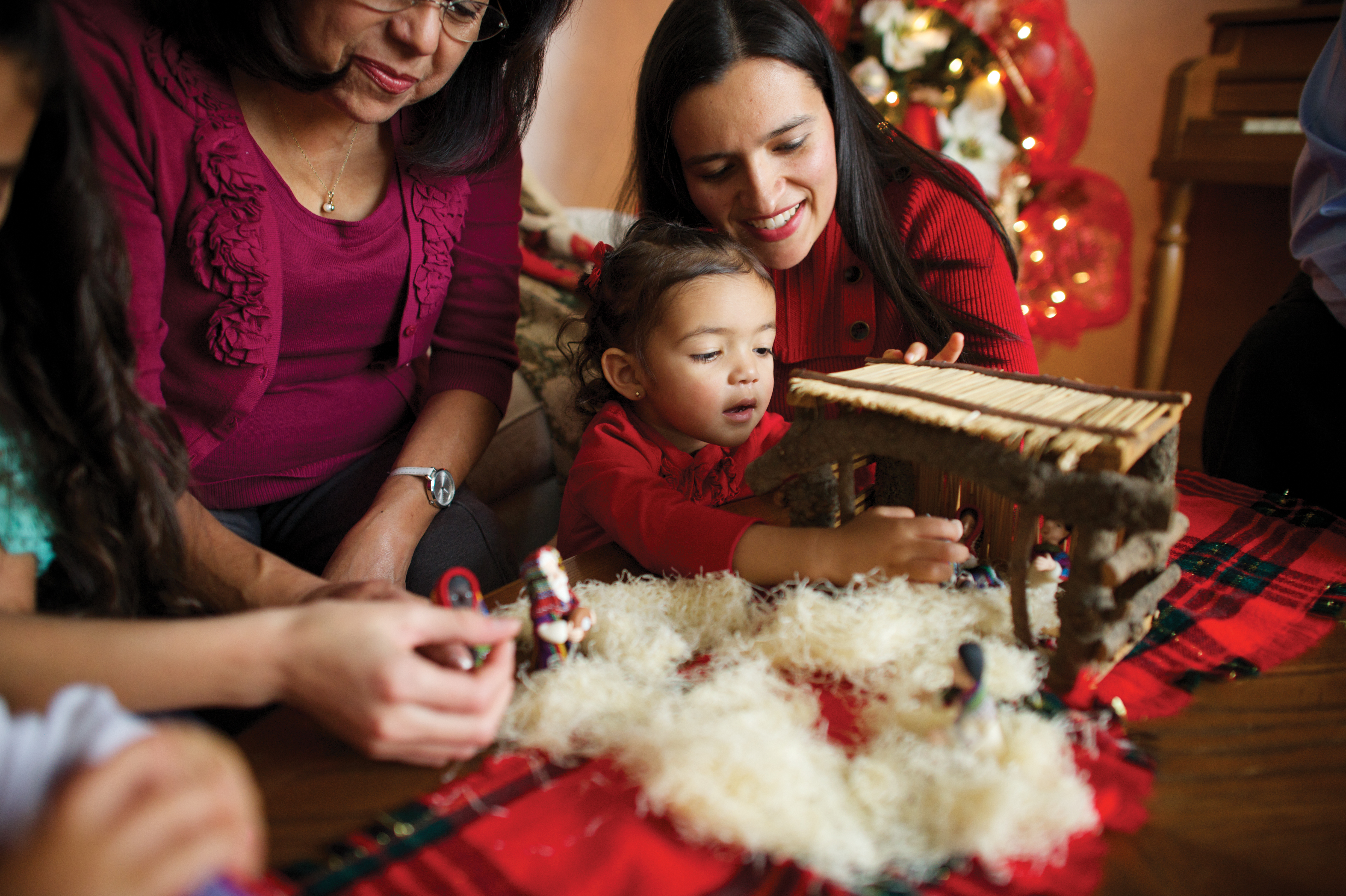 A young girl and her family standing around a table and setting up a small Nativity.