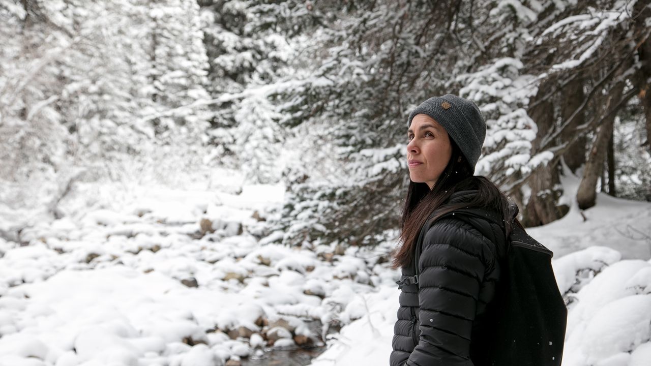 A woman walks through a snowy forest