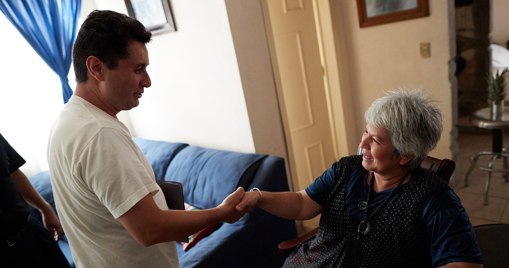 A man shakes the hand of an elderly woman after a ministering visit.