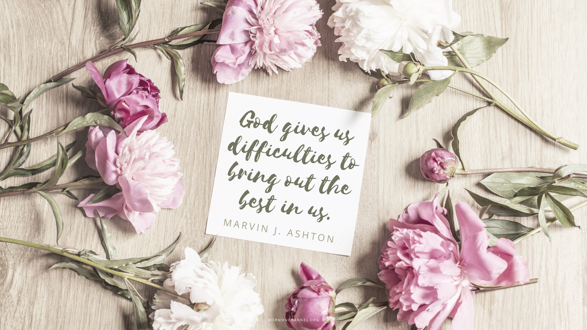 Pink flowers arranged around a note with a quote by Elder Marvin J. Ashton: “God gives us difficulties to bring out the best in us.”