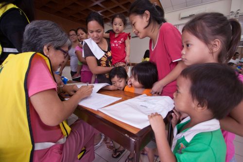 Philippines Immunization.  Workers and volunteers interacting with parents and children.