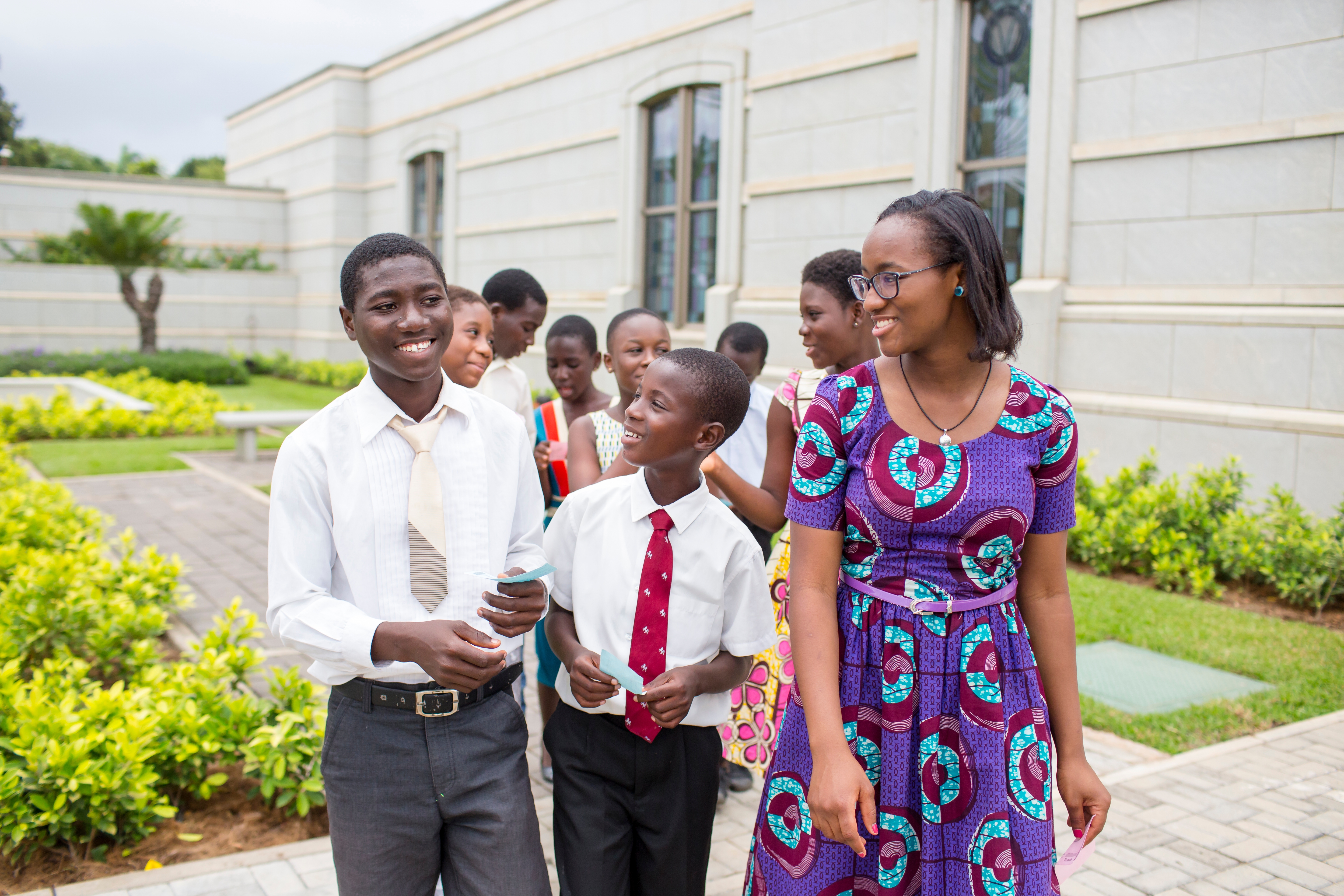 Several young men and young women walking outside the Accra Ghana Temple with ordinance cards