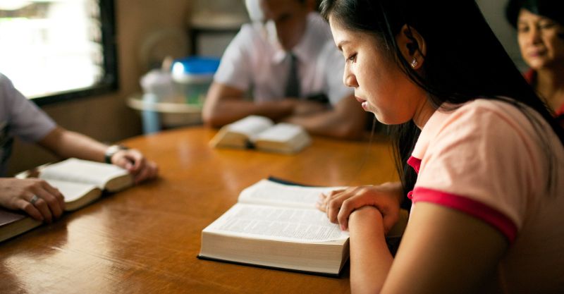 A woman studies the scriptures with missionaries