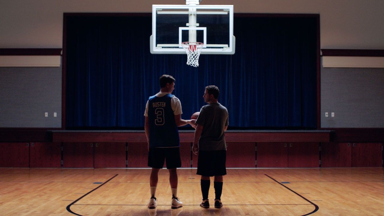 Two men standing next to each other under a basketball hoop