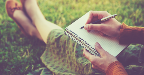 Girl Writing in Notebook on Grass