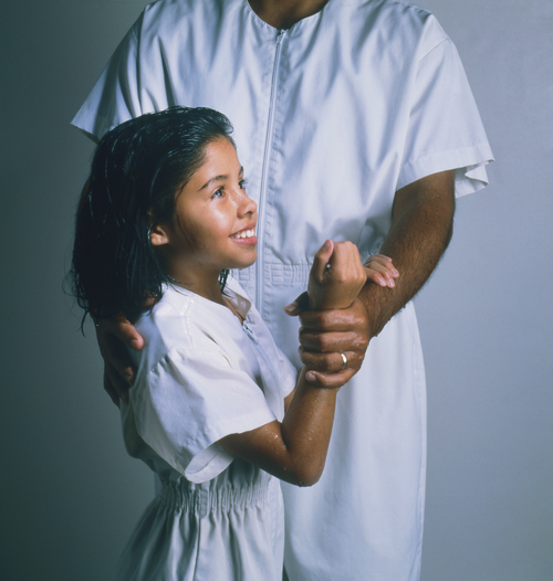 An eight-year-old girl and a priesthood holder dressed in white baptismal clothing, in position for baptism.