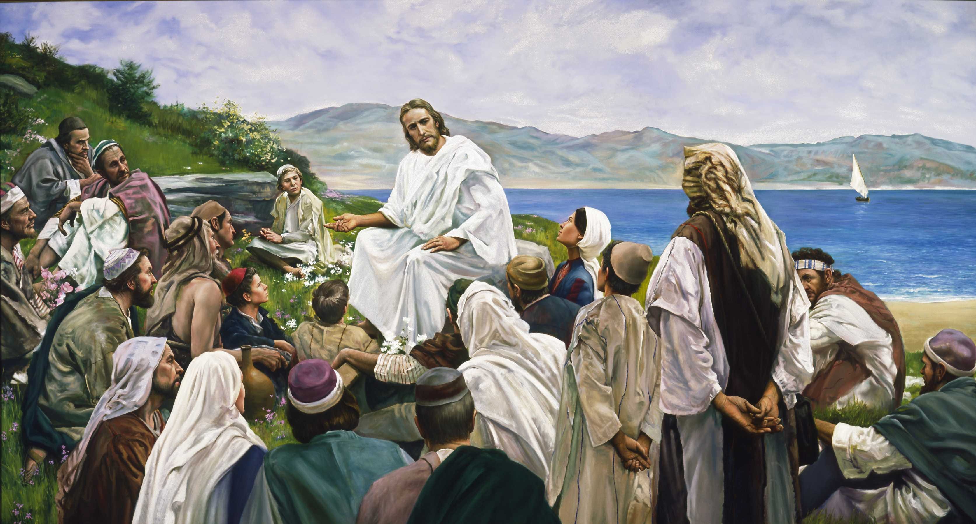 Jesus Christ sitting on a hillside preaching to a crowd of people. Mountains and sea are visible in the background. A reproduction by Grant Romney Clawson of the original "Sermon on the Mount" by Harry Anderson.