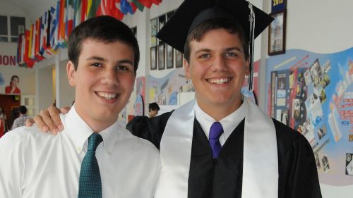 Color photo of two young men (brothers) standing in a school room, they are wearing ties, one has a graduate cap on. (Photo submitted by Spencer Belnap)