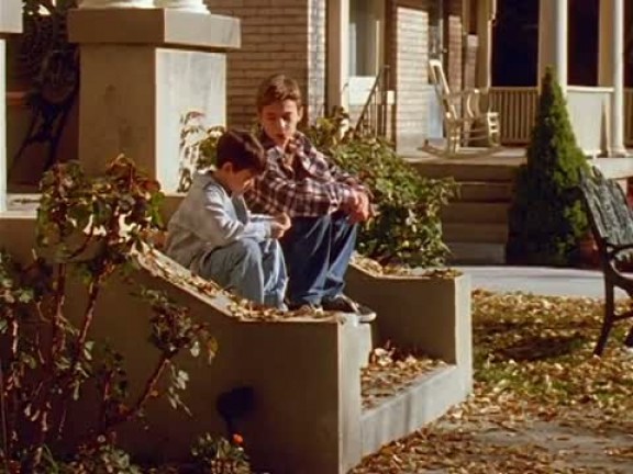 A photo of two young boys sitting on house steps talking in the fall.