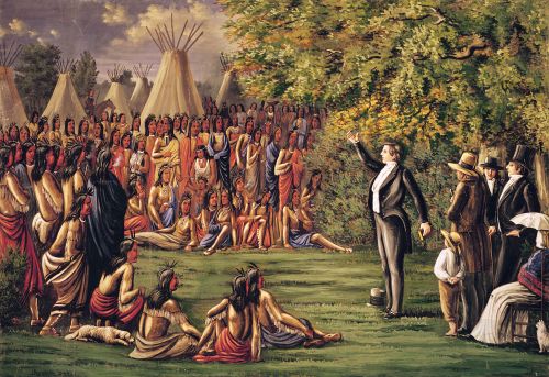 Joseph Smith preaching to a large group of Sac and Fox American Indians on August 12, 1841. The Indians are standing and/or sitting in a large semi-circle around Joseph Smith. Indian tepees are in the background. Joseph Smith, wearing a dark suit, stands with one arm raised above his head. He holds a book in his other hand. A small group of church members are standing behind Joseph Smith. Painting number 12 of the 23 paintings in the "Mormon Panorama" series.