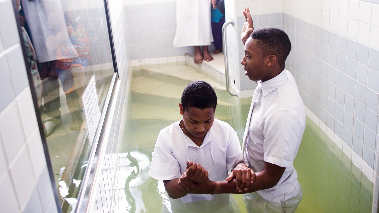 Un joven se bautiza en una pila bautismal de una capilla