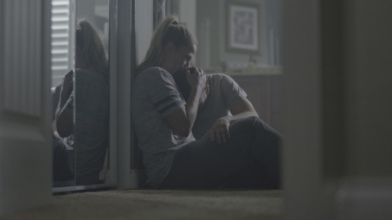 A mother sits in a kitchen comforting her son