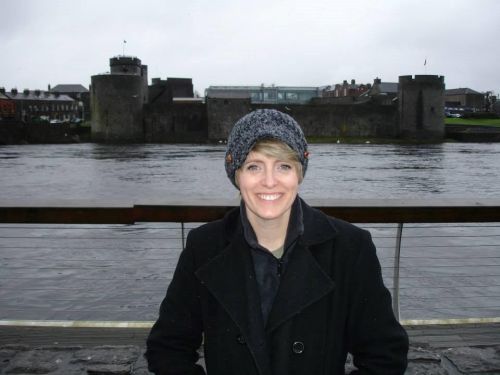 Color photo of a woman dressed in warm clothing, standing in front of a castle and river. (Photo submitted by Kristen Jones)