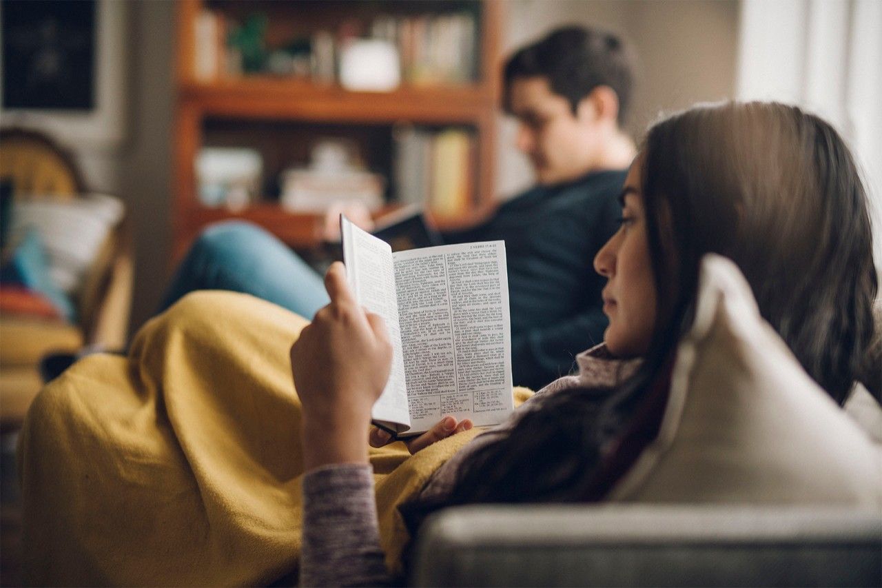 Une femme lisant le Livre de Mormon sur un canapé