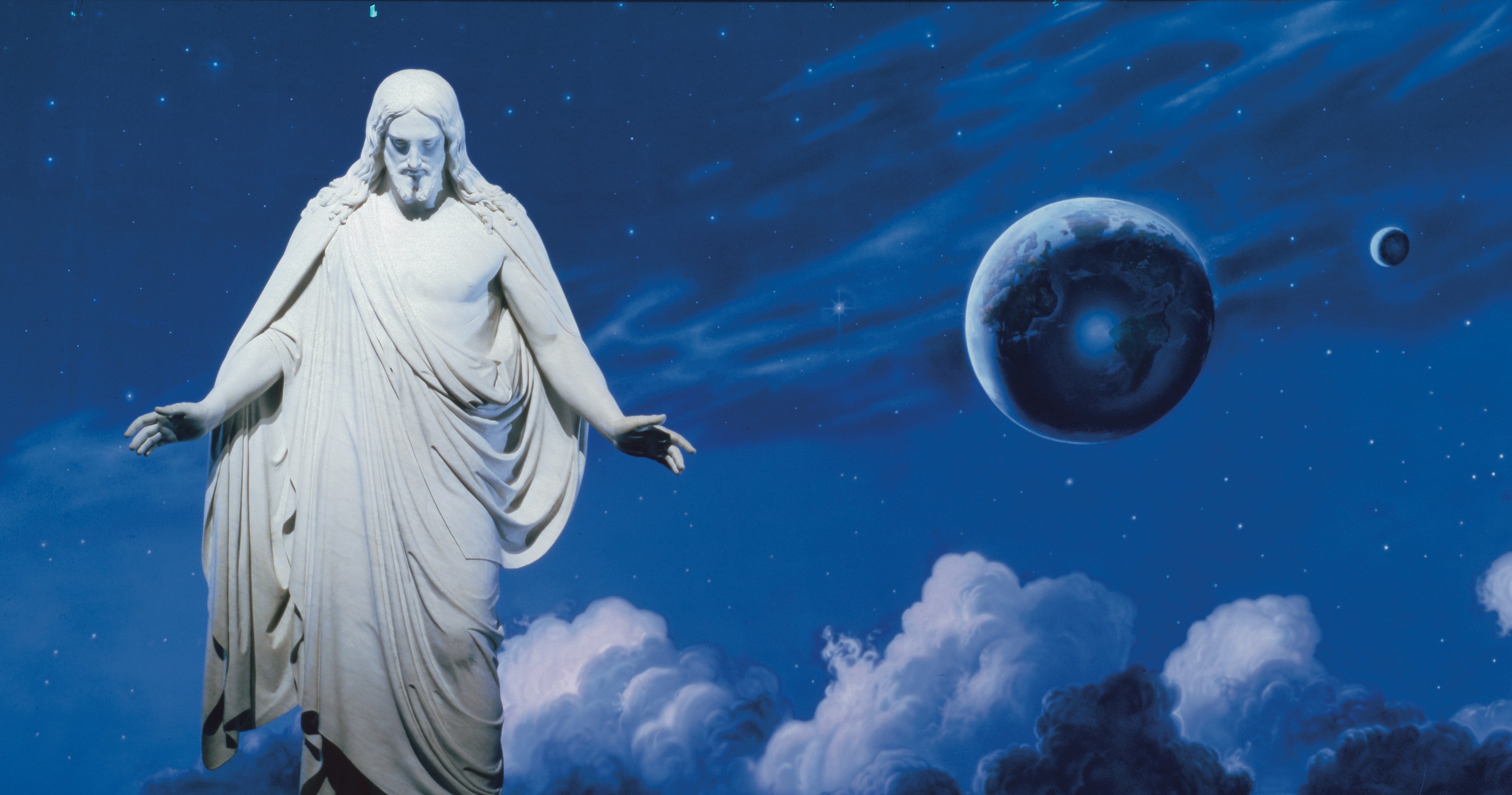 The resurrected Jesus Christ standing with His arms slightly extended. The wounds of the Crucifixion are visible in the hands, feet and side of Christ.  The "Universe" mural by Sidney King is visible behind the Christus statue.