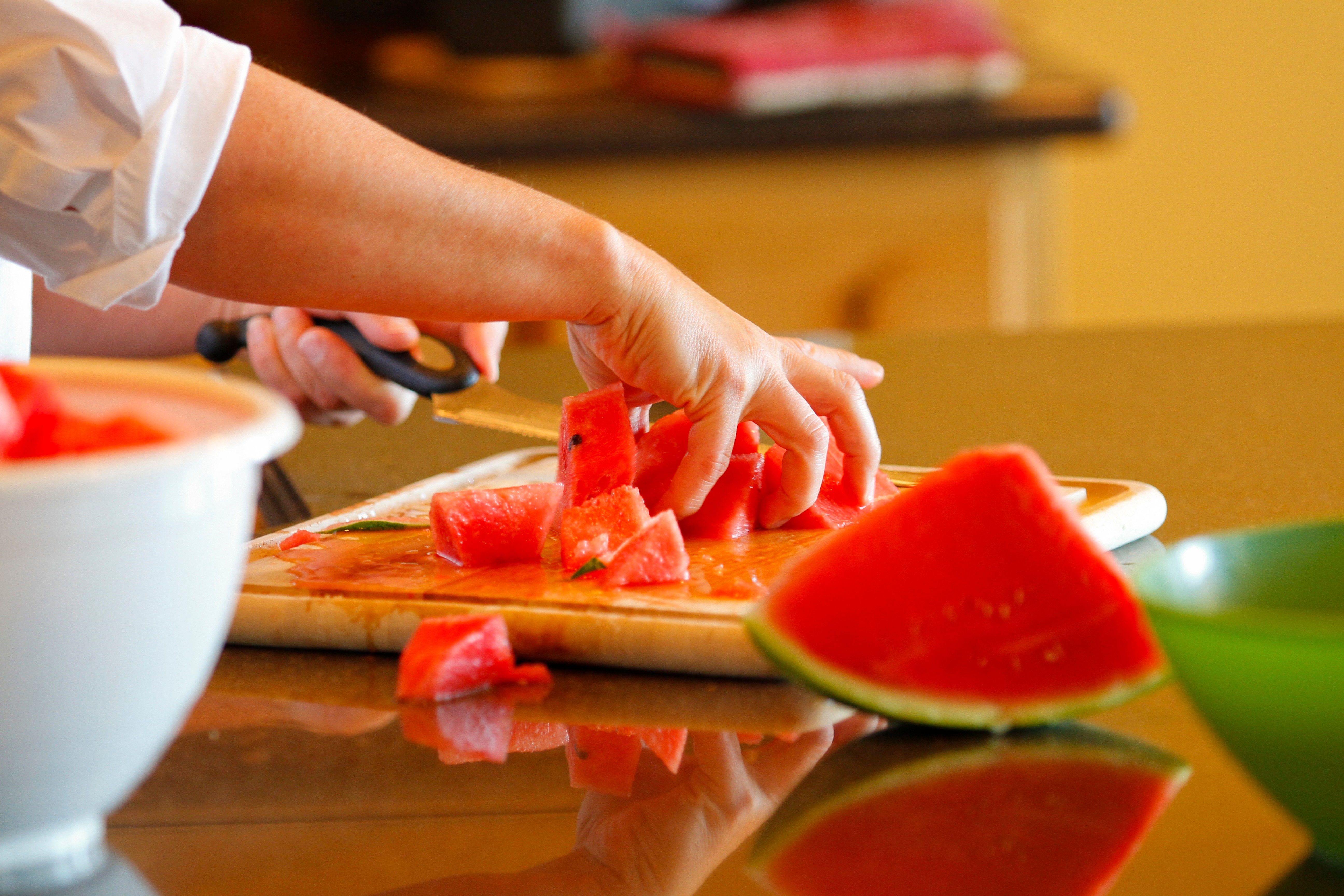 A food preparer slicing watermelon.  