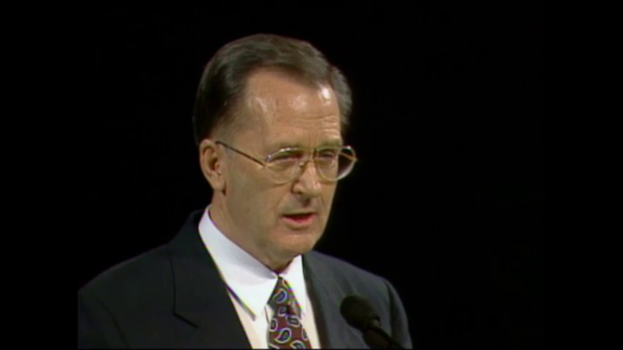A photo of Elder Jack H. Goaslind standing at the pulpit of the General Conference Center.