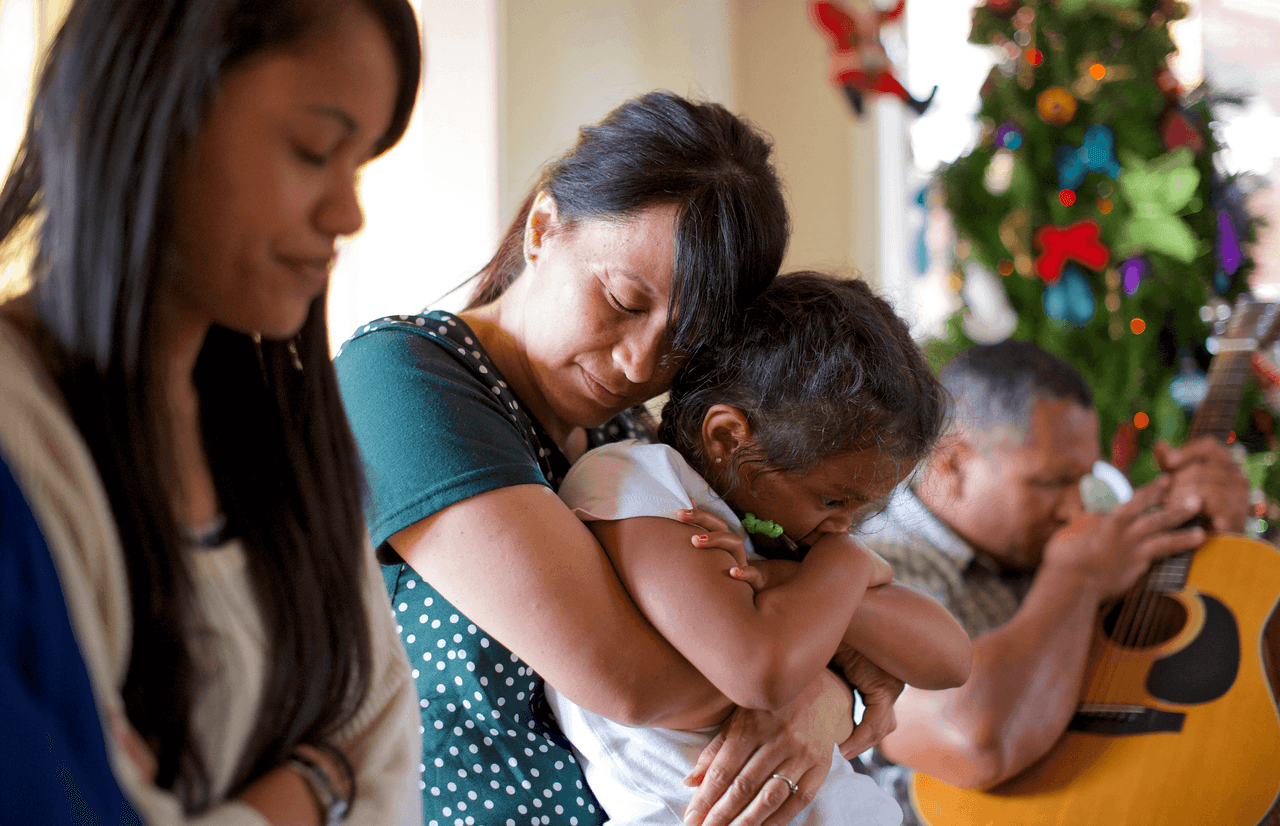Um casal e seus filhos cruzam os braços em oração