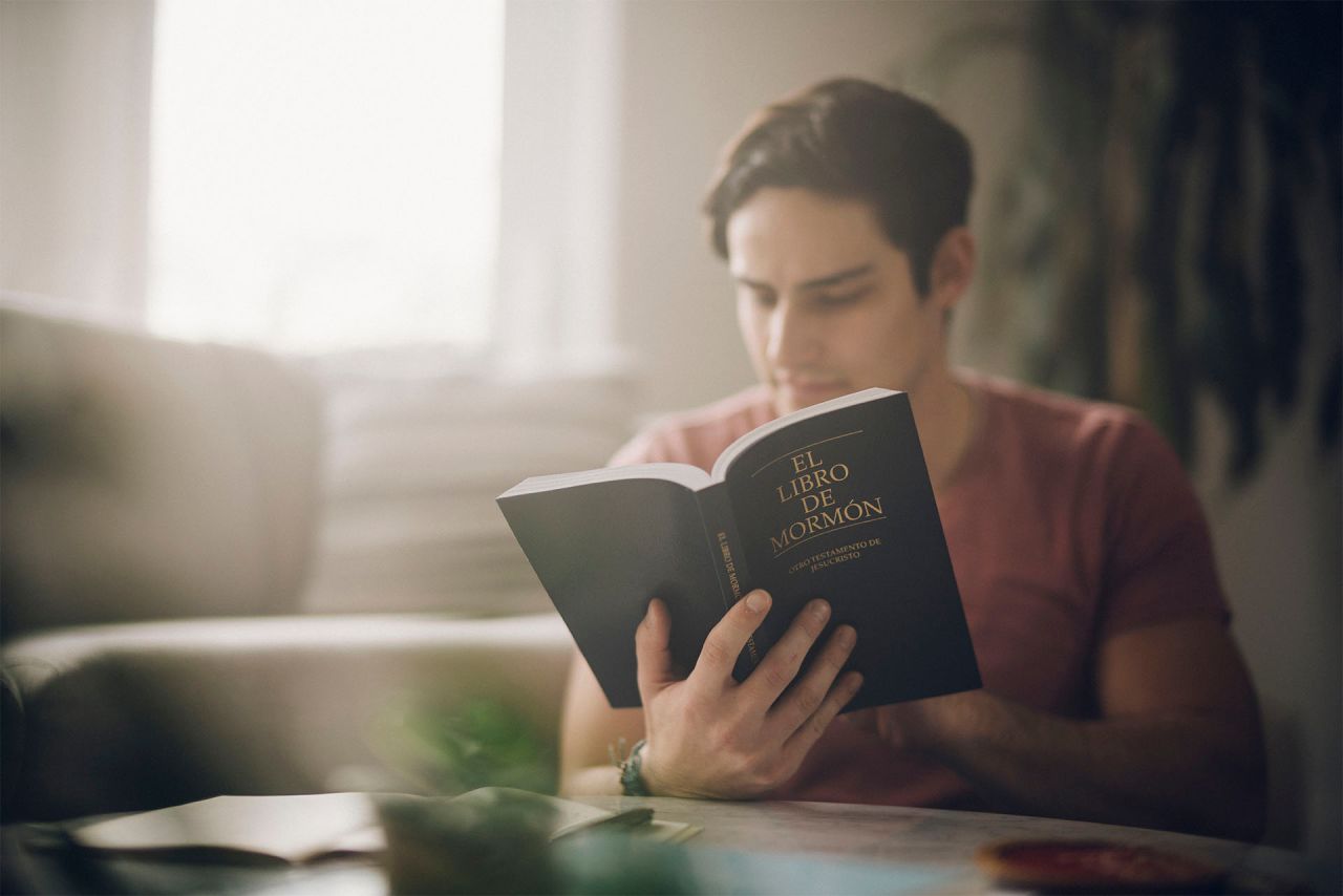 Un hombre estudia el Libro de Mormón en la sala de estar
