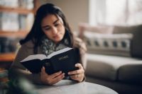 Una joven se sienta a la mesa de su cocina para estudiar la Biblia
