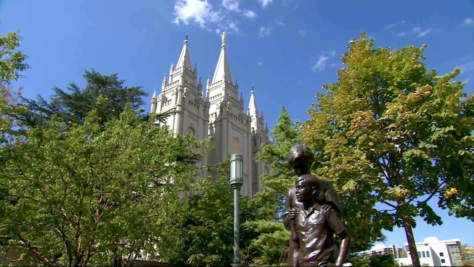 A picture of the Salt Lake Temple with trees and a statue framing it.