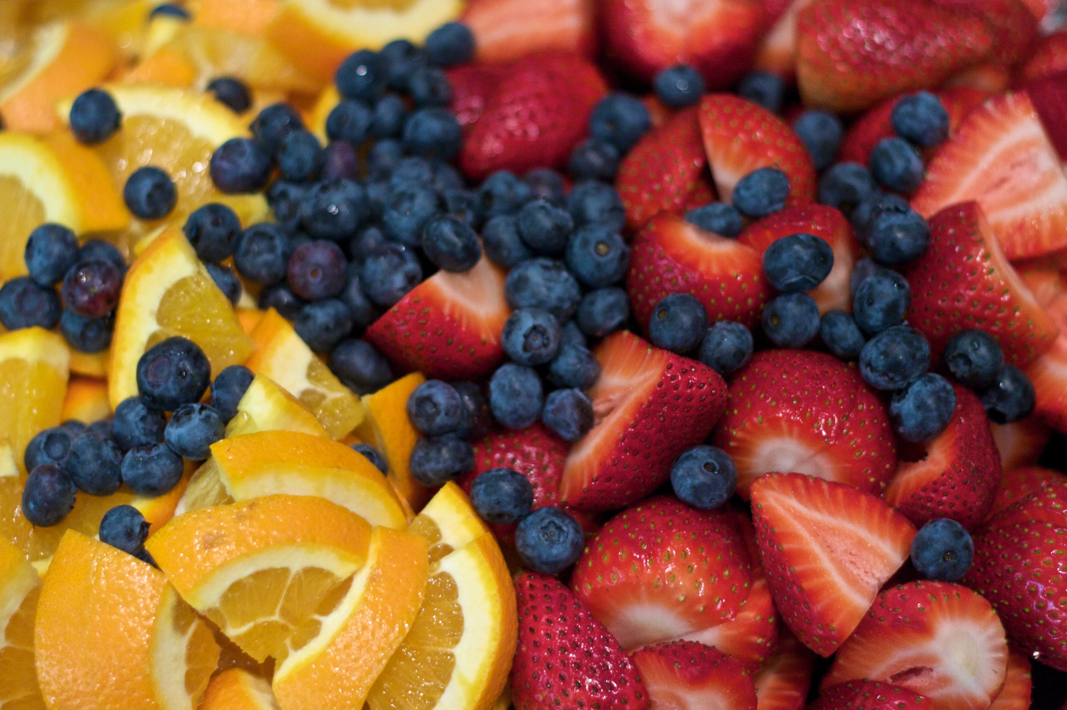 An image of sliced oranges, blueberries, and sliced strawberries.