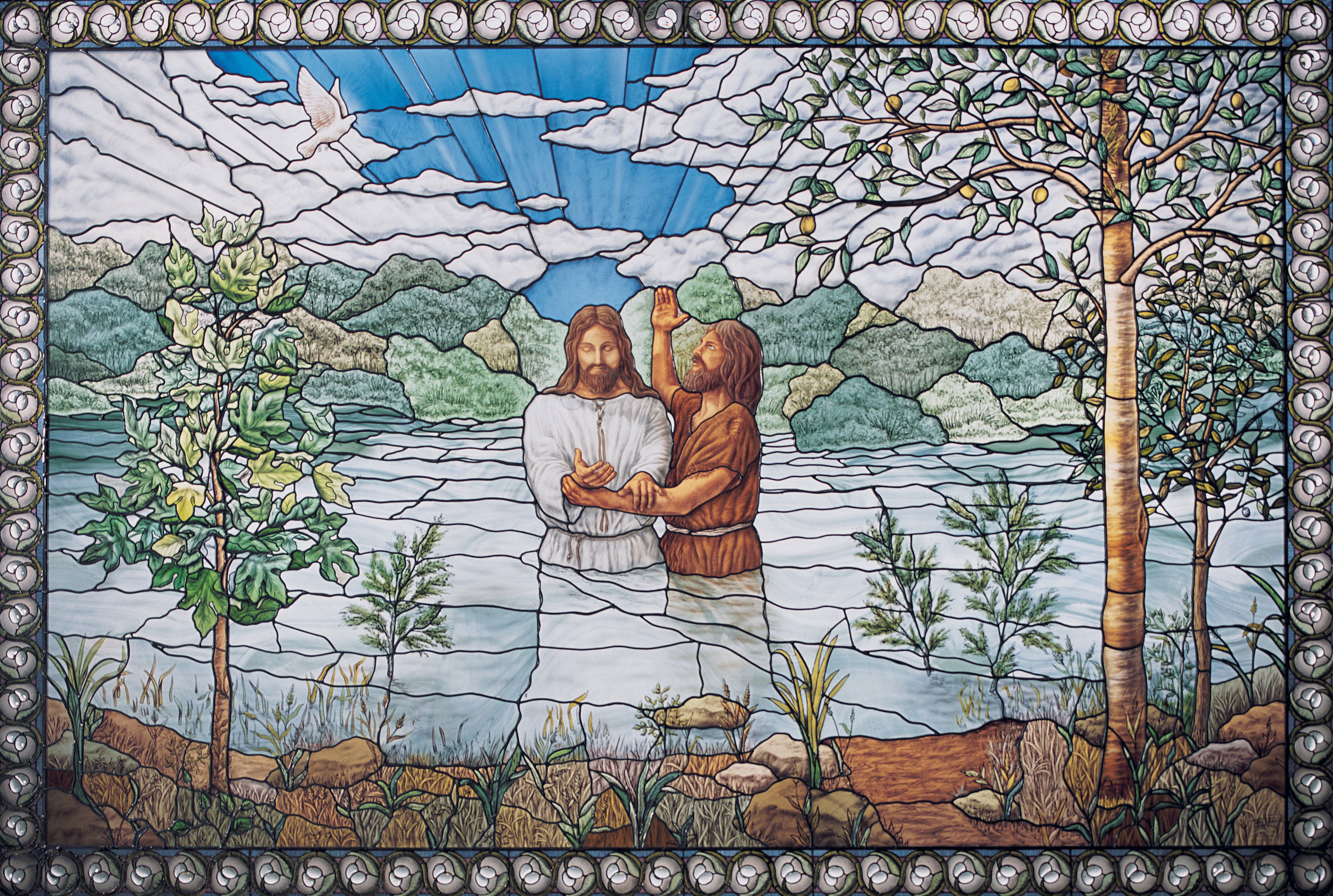 A stained glass window from the Nauvoo Temple depicting Christ being baptized by John the Baptist.