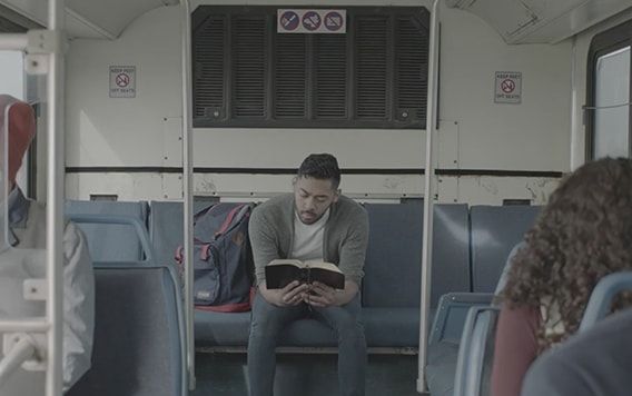 Joven leyendo las escrituras en un autobús