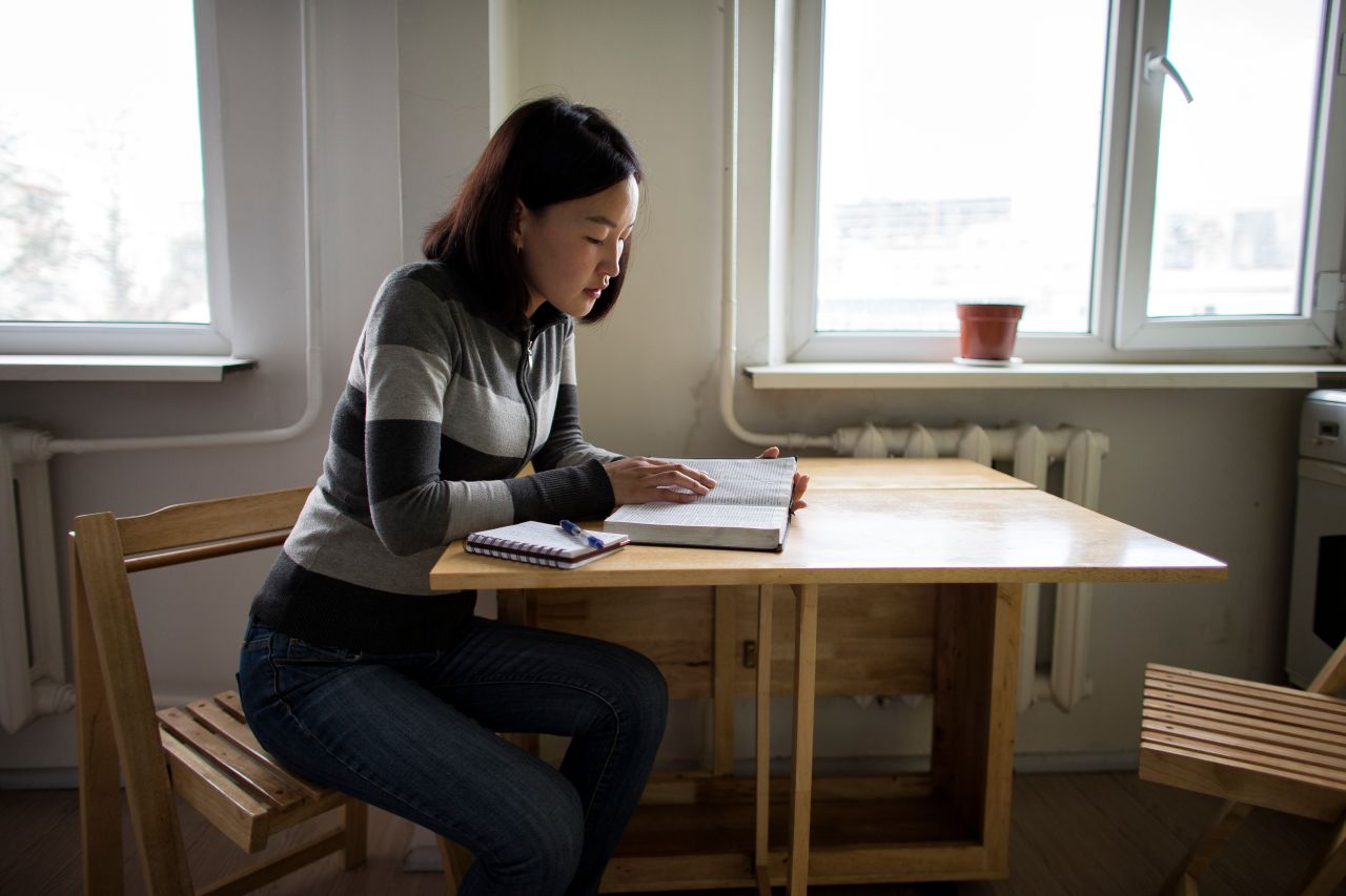 A woman studies the Book of Mormon at her kitchen table
