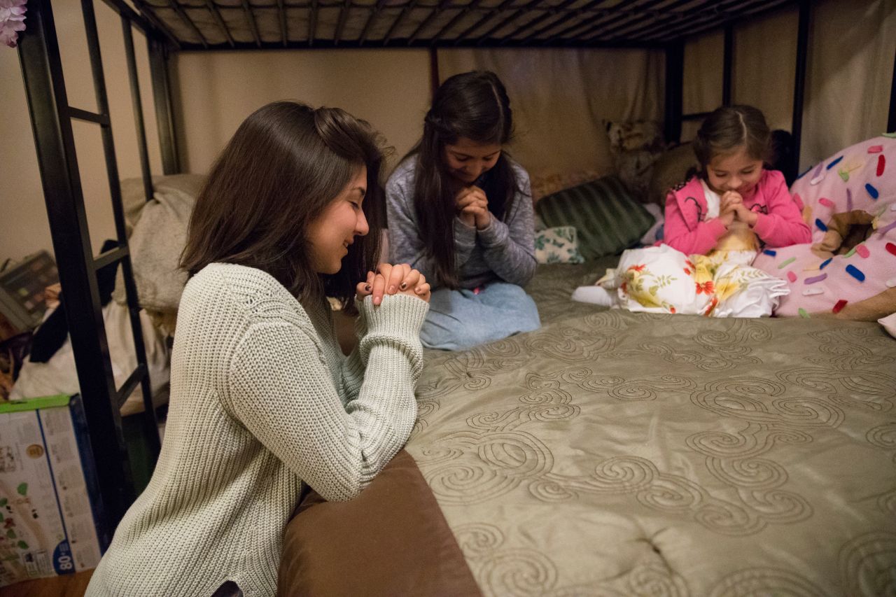 Una madre ora con sus hijas antes de ir a dormir