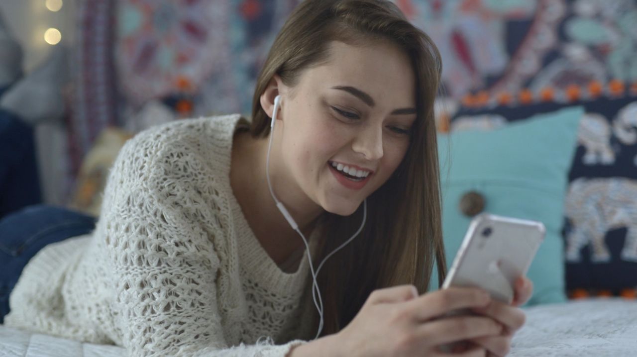 Une fille sourit en regardant son portable