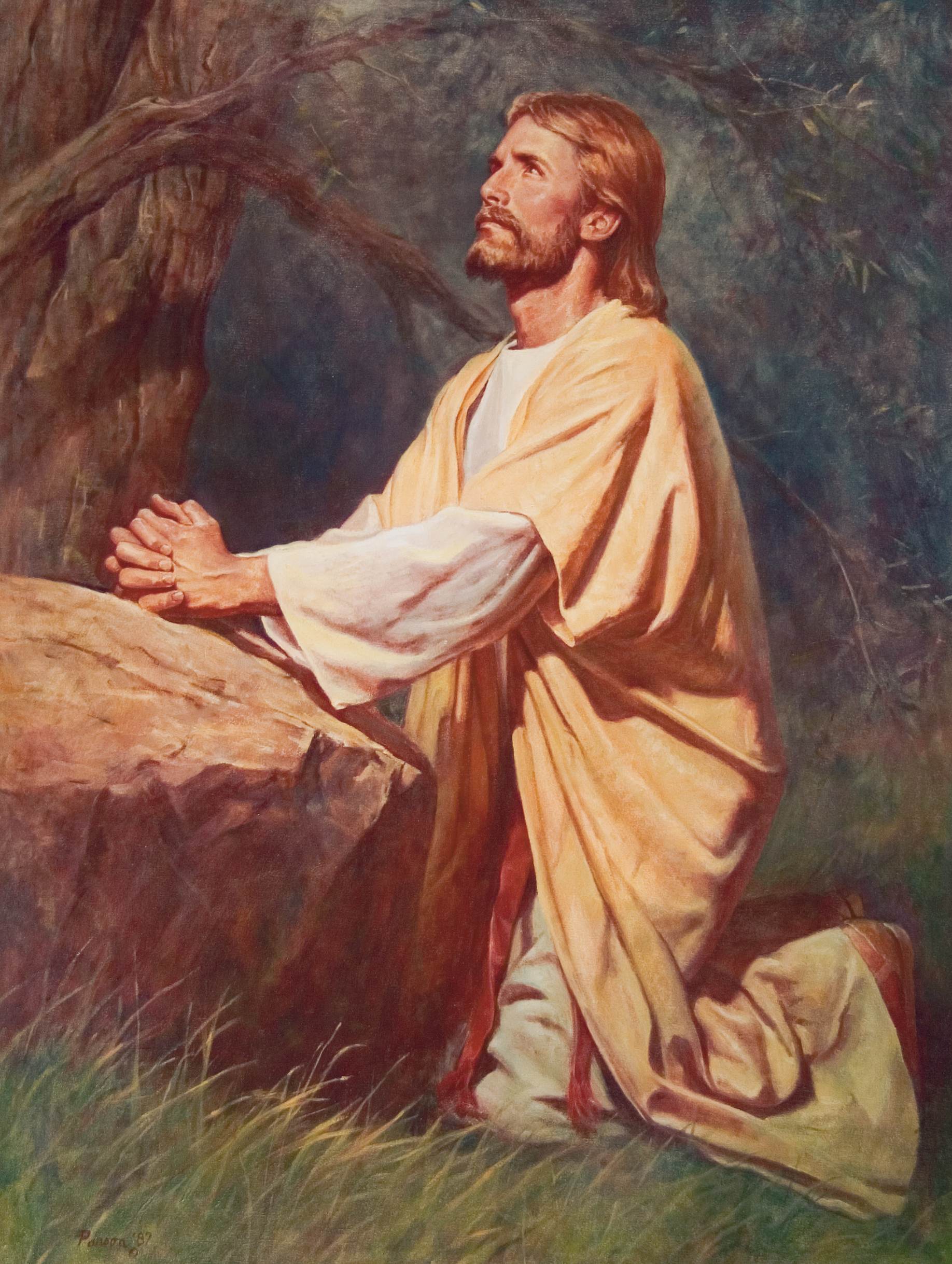Christ in yellow and white robes, kneeling in the grass next to a large rock, with His hands clasped, looking upward.
