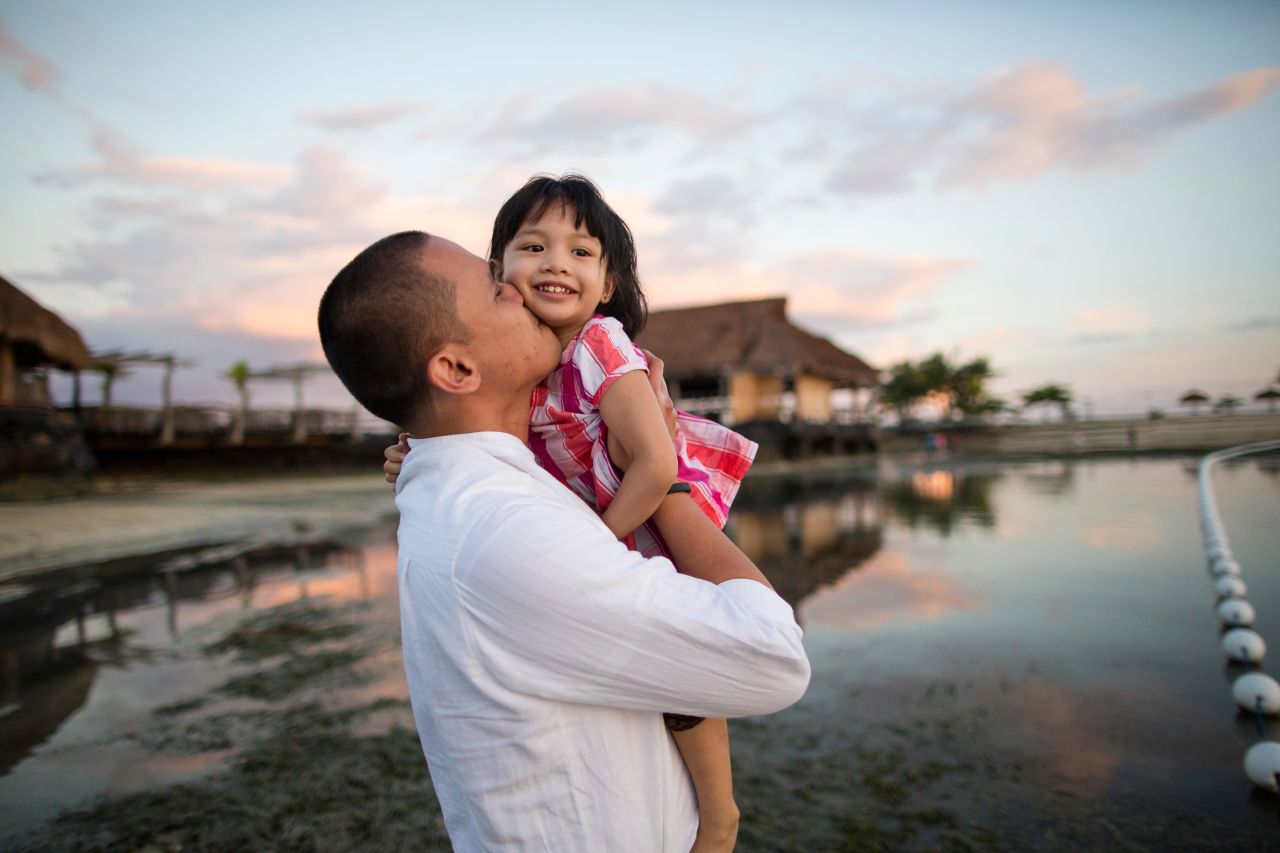 Padre abraza a su pequeña hija en la playa