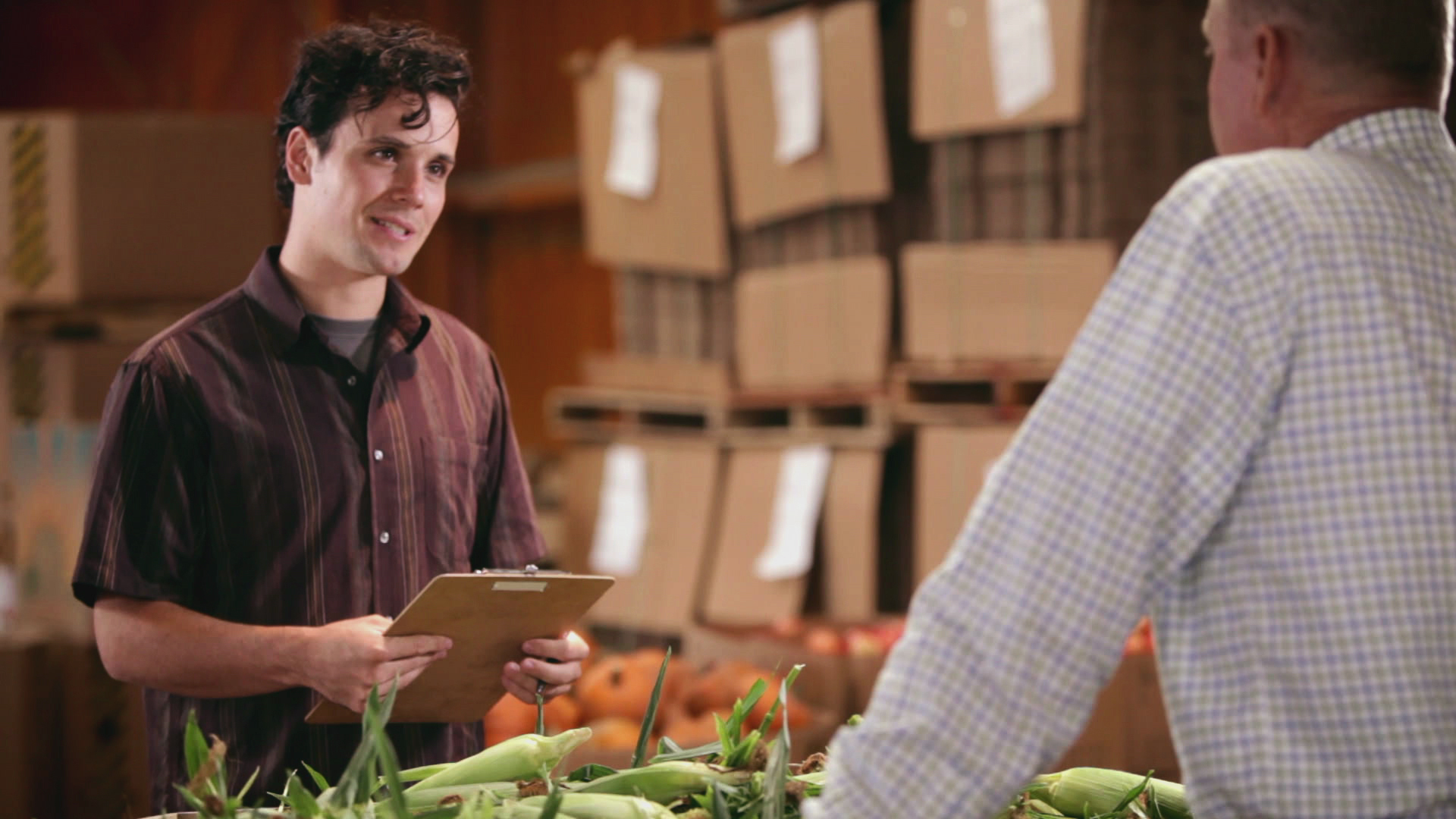 A photo of a man interviewing to a food supplier, holding a clipboard.