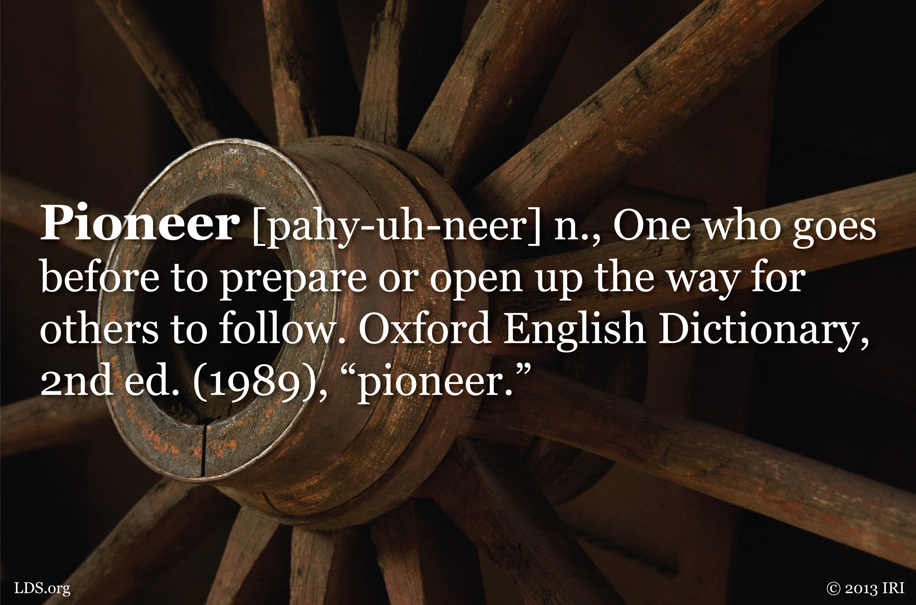 An image of a wagon wheel with the definition of the word pioneer printed over the top.