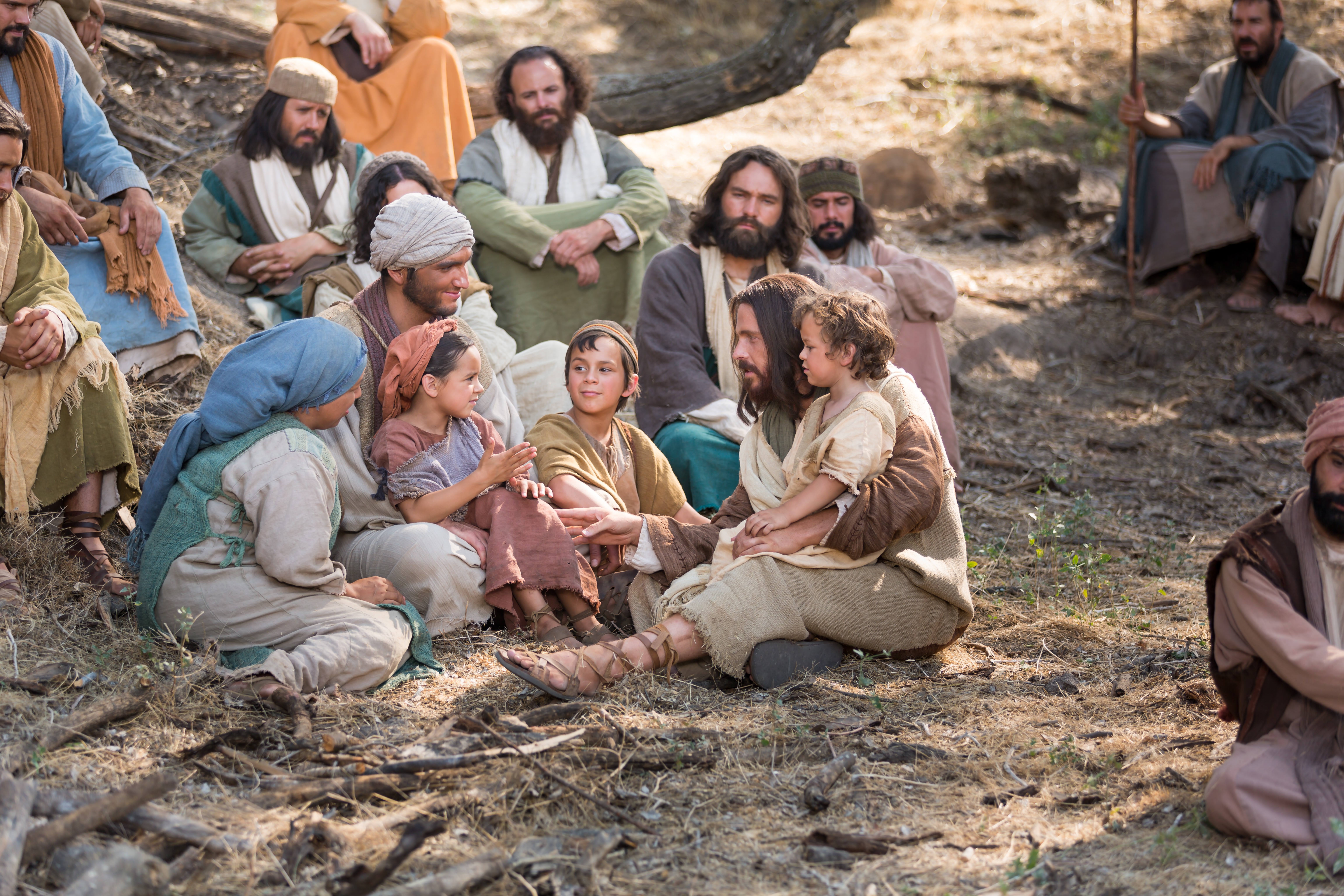 Jesus is sitting down on the ground with a young boy in his lap and surrounded by mothers and other people.  Outtakes include Jesus holding children and walking with them, his disciples with him, Jesus and Peter, Jesus with Peter and James and some of the children.