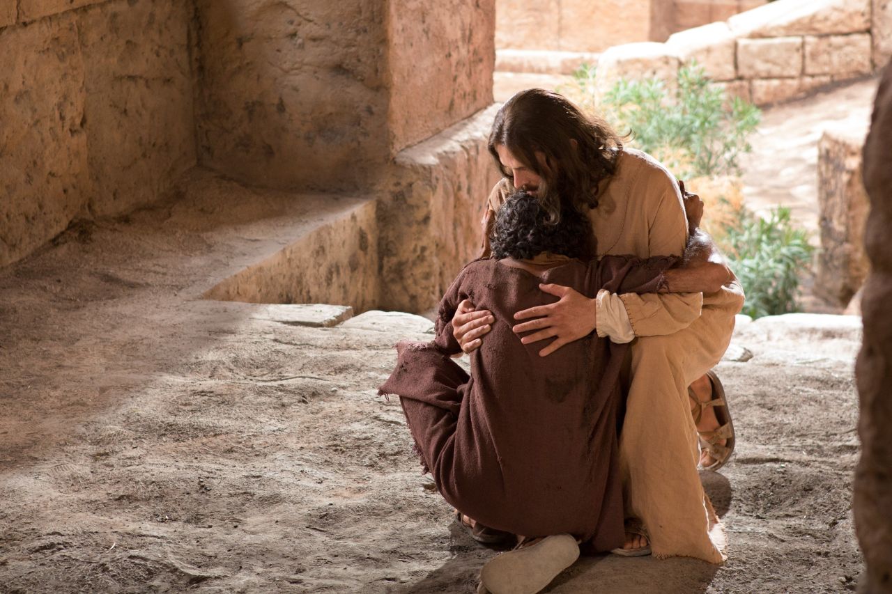 Un hombre y Jesús se funden en un abrazo mientras caen al suelo
