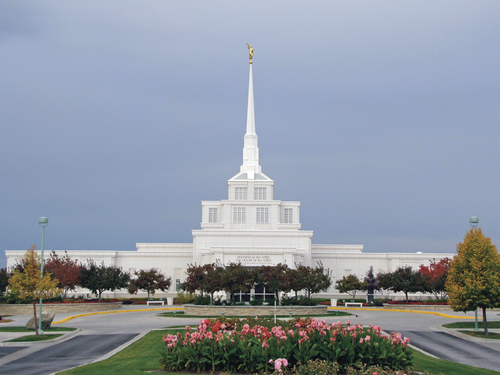 A view of the front of the Billings Montana Temple on a fall day, with flowers in the foreground.