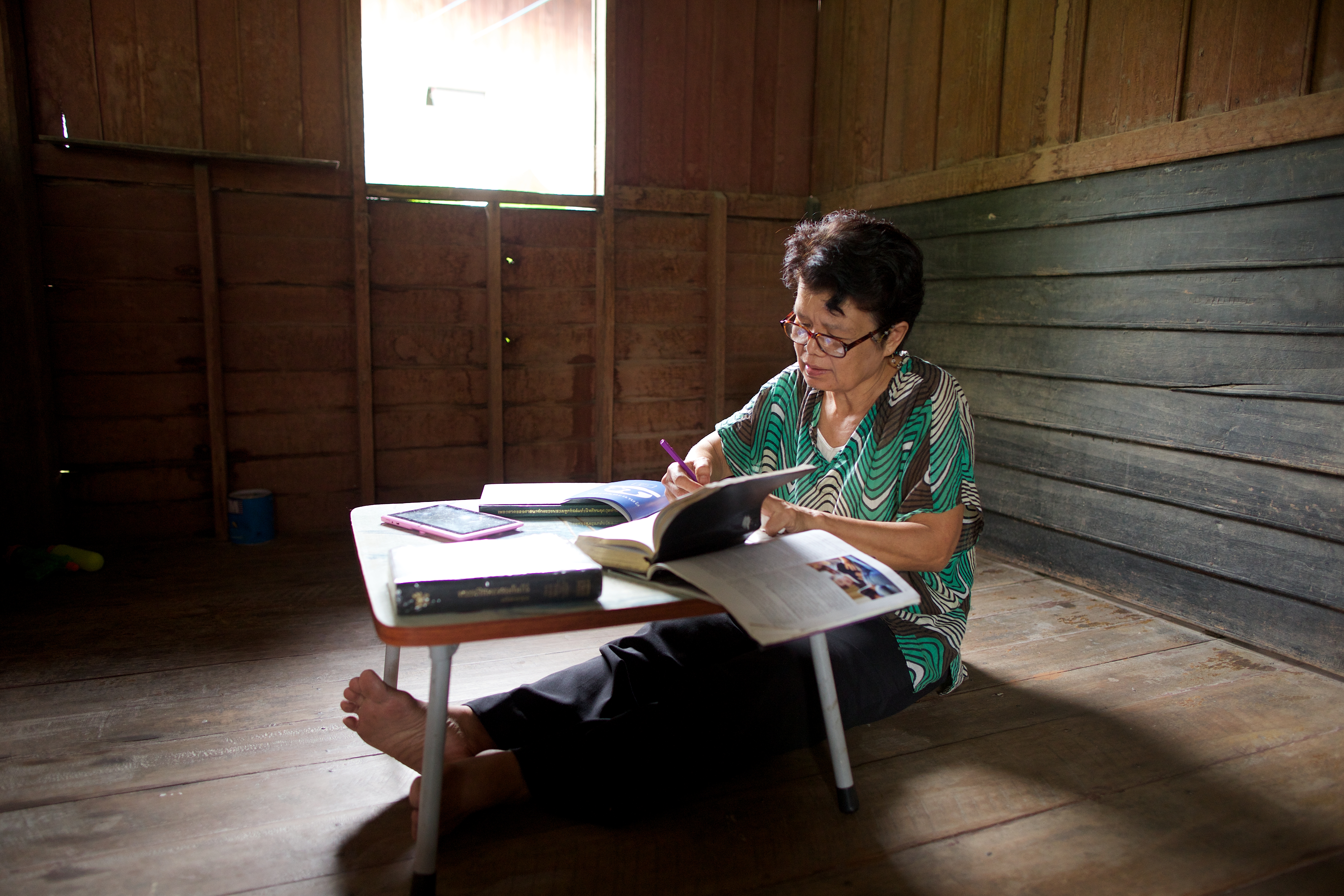 Elderly woman completing her family tree booklet in Thailand