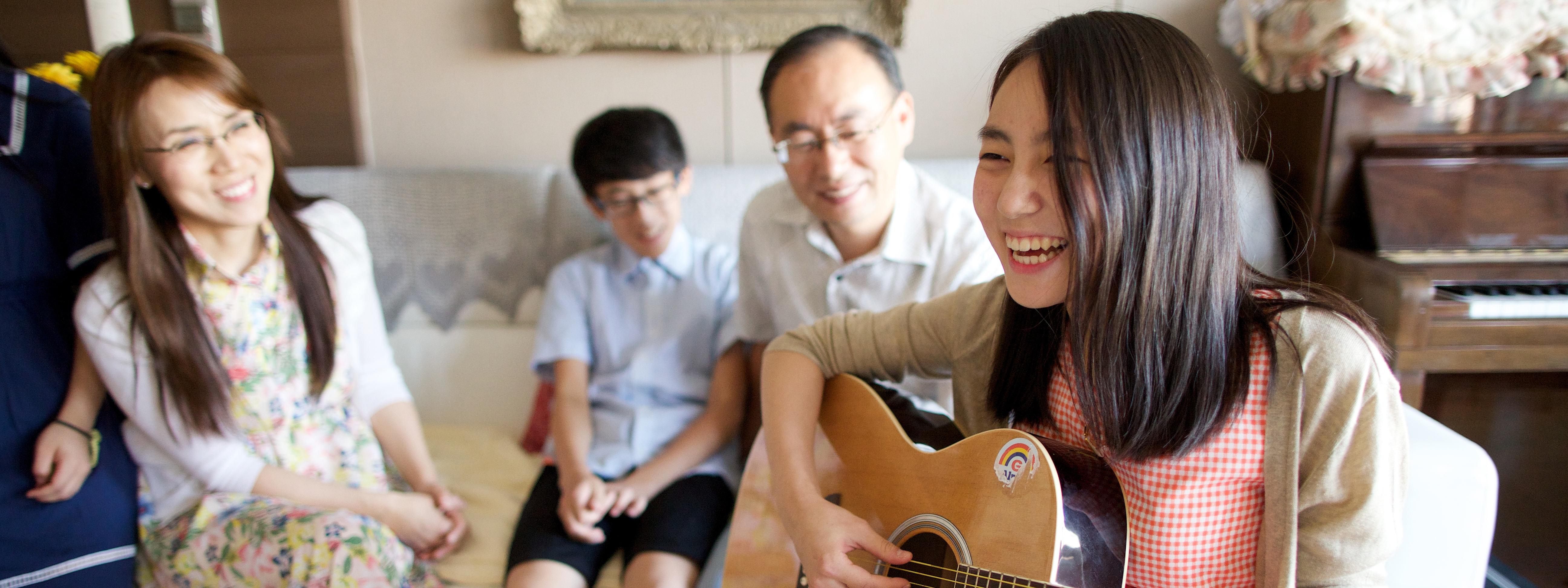 Young woman playing guitar with her family present