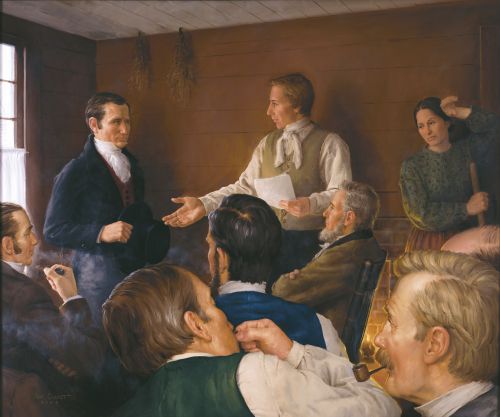 Joseph Smith with a paper in his hand talking with men at the School of the Prophets about the Word of Wisdom. Some of the men are smoking or chewing tobacco. Emma Smith is holding a broom or mop.