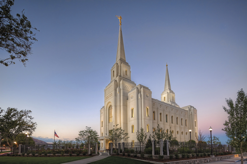 A side view of the Brigham City Utah Temple in the evening, with lights illuminating the temple from within and without.